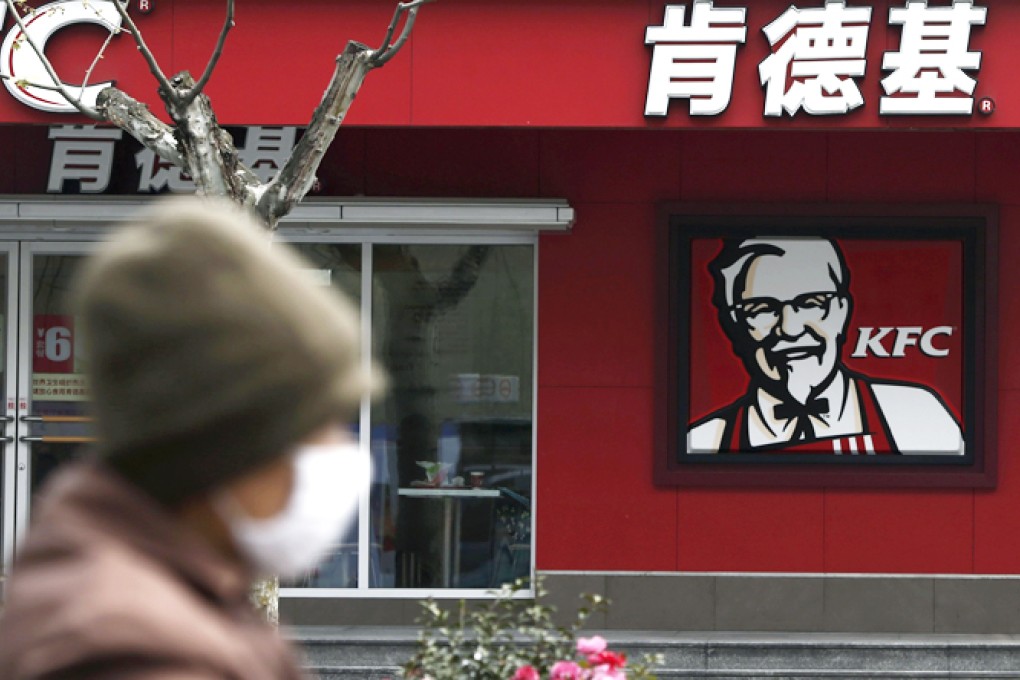 A woman, wearing a mask, rides past a KFC restaurant in Shanghai April 11, 2013.