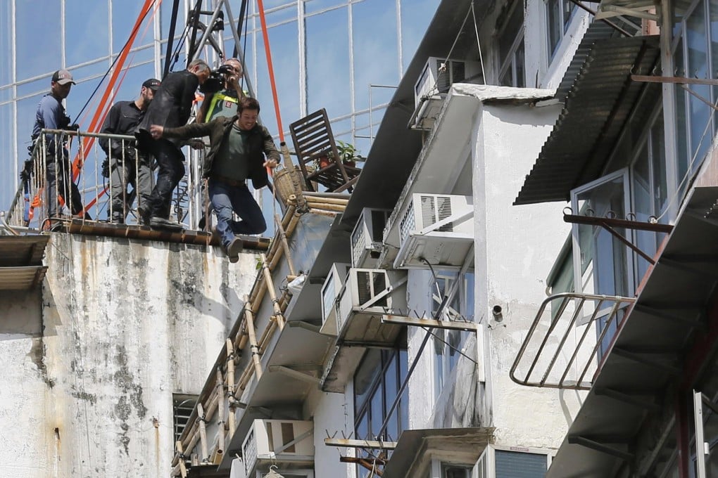 An actor jumps onto the roof of a block of flats during filming in Quarry Bay yesterday. Photo: AP