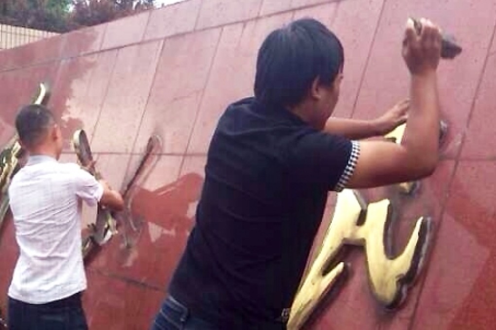 Yuyao residents take down the "Serve the People" logo outside their municipal government compound on Tuesday. Screenshot via Sina Weibo