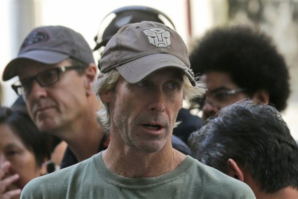 American film director Michael Bay speaks with his film crew during the filming of a scene for their latest movie "Transformers 4: Age of Extinction" in Hong Kong Friday, Oct. 18, 2013. Bay was attacked on Thursday and slightly injured on the set of the fourth installment of the "Transformers" movie series filming in Hong Kong, police said. The spokeswoman said Bay suffered a minor injury to his face but declined medical treatment. (AP Photo/Kin Cheung)
