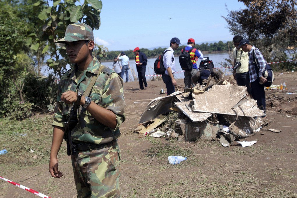 A Laotian soldier stands guard as French investigators gather around the wreckage of a Lao Airlines plane. Photo: AP