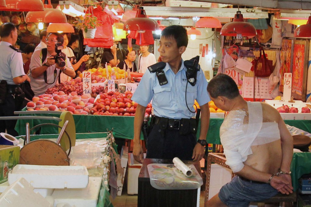 Police officer arrests the fruit stall owner (with handcuffs) in Po On Road Market, Cheung Sha Wan.
