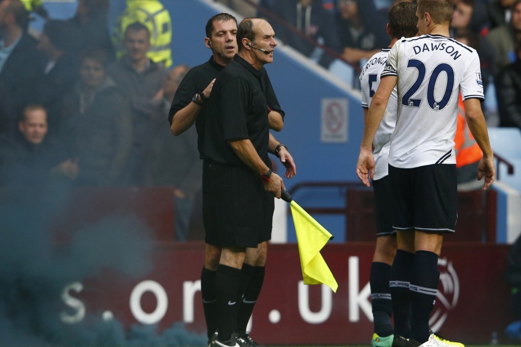 Referee Phil Dowd checks the back of assistant referee David Bryan after he was hit by a smoke canister during the match between Aston Villa and Tottenham Hotspur at Villa Park. Photo: Reuters