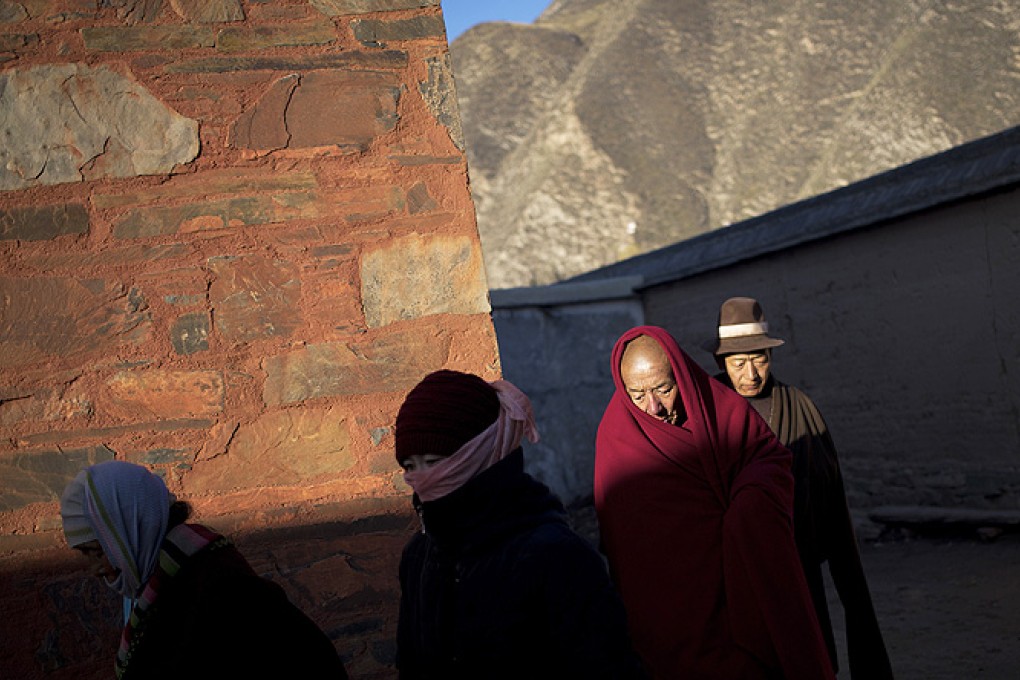 A Tibetan monk and pilgrims circle a Buddhist temple to offer prayers near the historic Labrang Monastery in Xiahe, Gansu province, China. Photo: AP