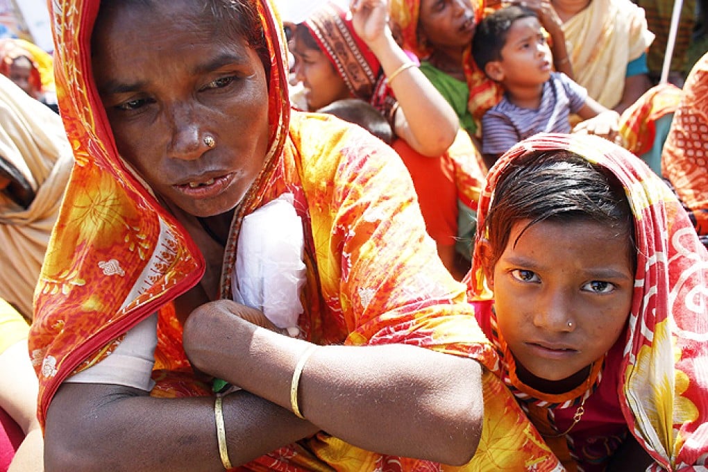 A garment worker who survived the Rana Plaza building collapse, takes part in a protest with her child to demand for compensation, on the six month anniversary of the incident, in front of the site in Savar on Thursday. Photo: Reuters