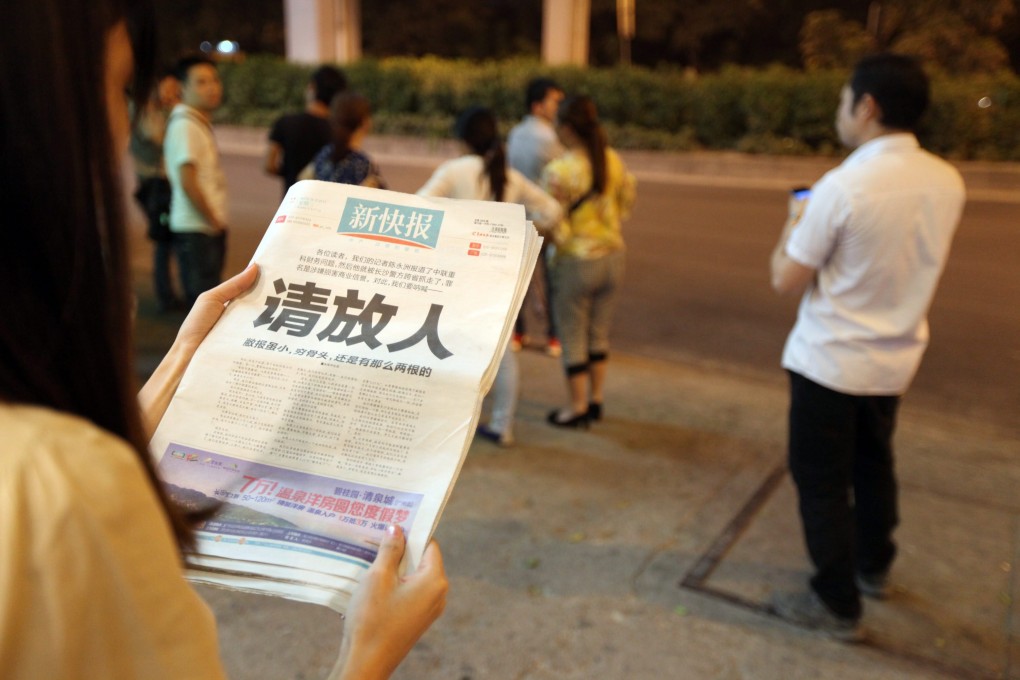 A Chinese woman reads the front page of the New Express, which features a plea asking the police to release its reporter Chen Yongzhou. Photo: EPA