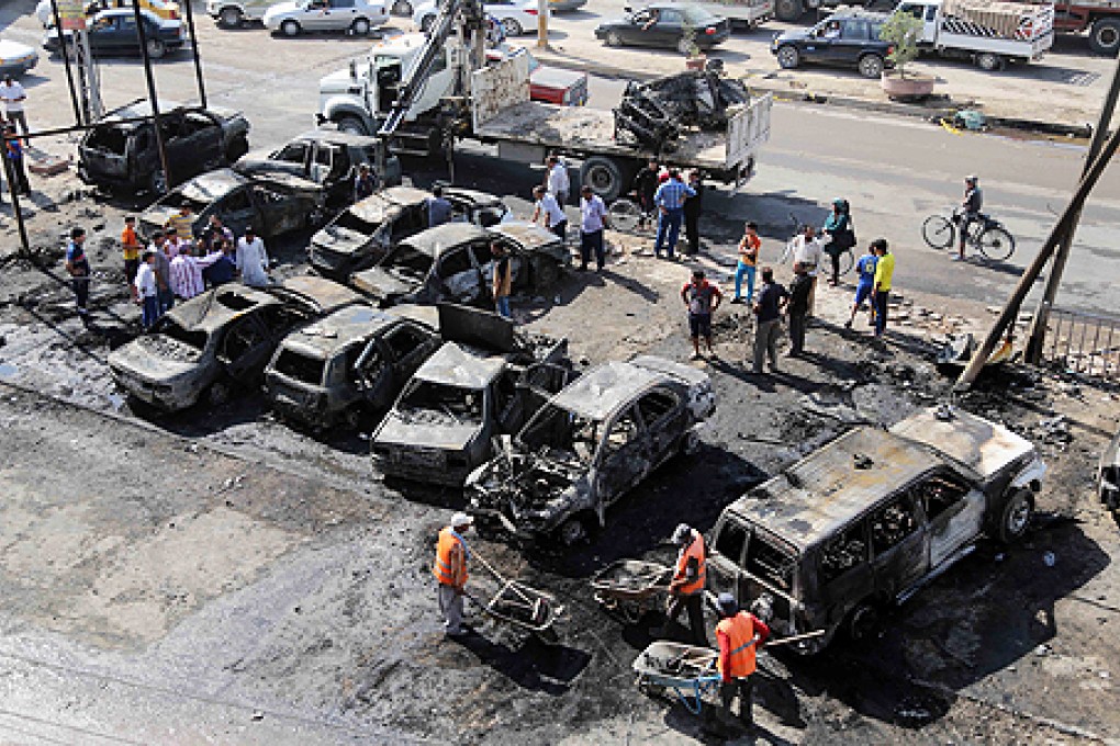 Workers clear debris while citizens inspect the site of a car bomb attack in the Shaab neighbourhood of Baghdad on Sunday. Photo: AP