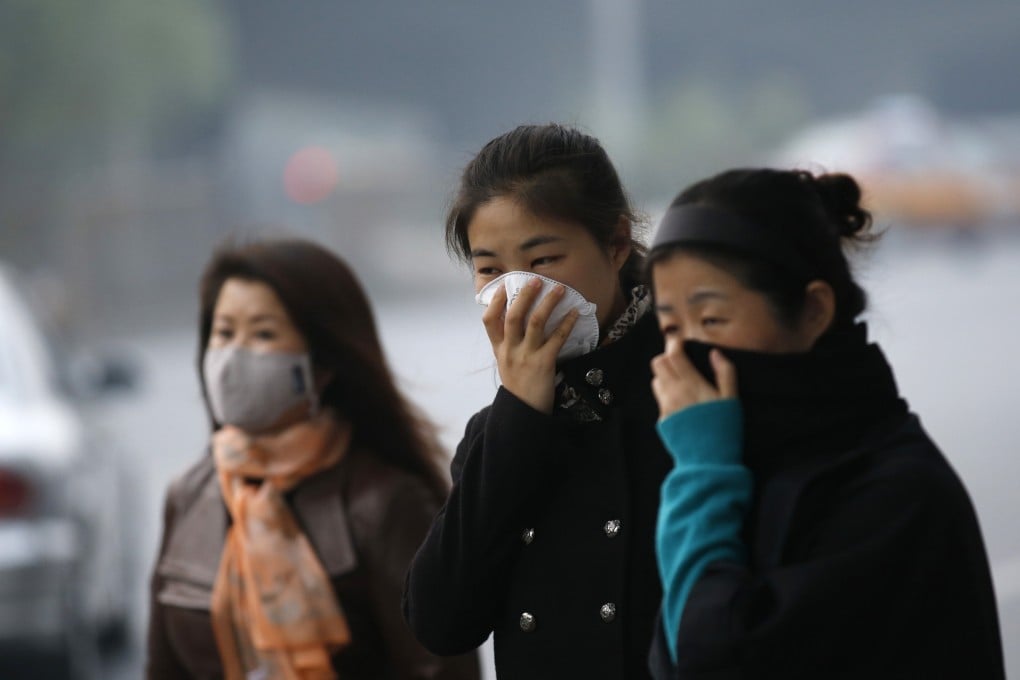 Women wear masks while waiting for bus on Monday in Beijing. Photo: Reuters