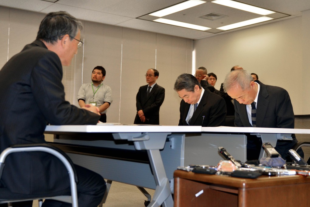 Tepco president Naomi Hirose (right) and vice president Zengo Aizawa (second right) bow their heads before Nuclear Regulation Authority Chairman Shunichi Tanaka (left) on Monday. Photo: AFP