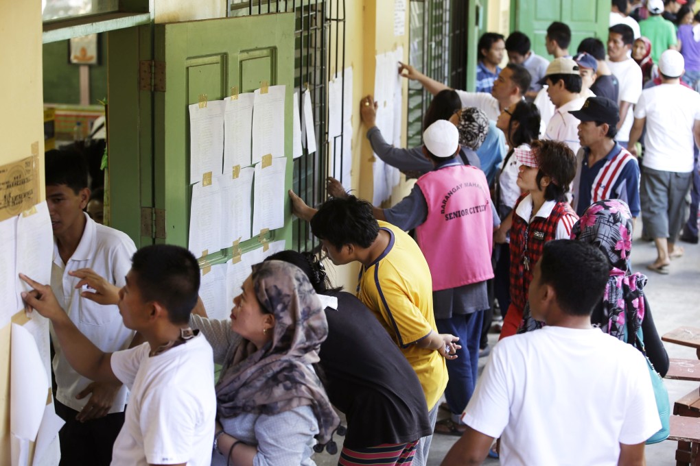 Filipino voters check their names outside a polling station prior to voting their candidates in the country's village elections at suburban Taguig city, east of Manila, Philippines, on Monday. Photo: AP