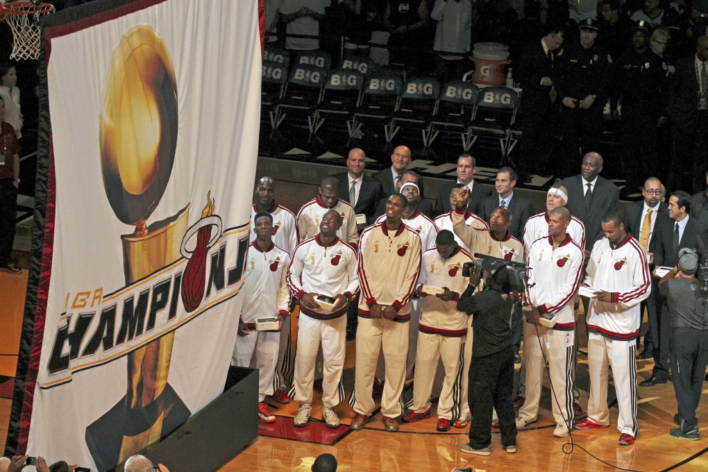 Miami Heat players and coaches watch as the 2013 NBA championship banner is raised before the Heat's season-opener   against the Chicago Bulls. Photo: AP