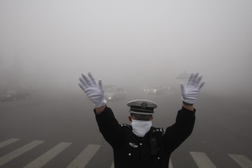A policeman directs traffic in the heavy smog in Harbin in Heilongjiang province. Photo: EPA