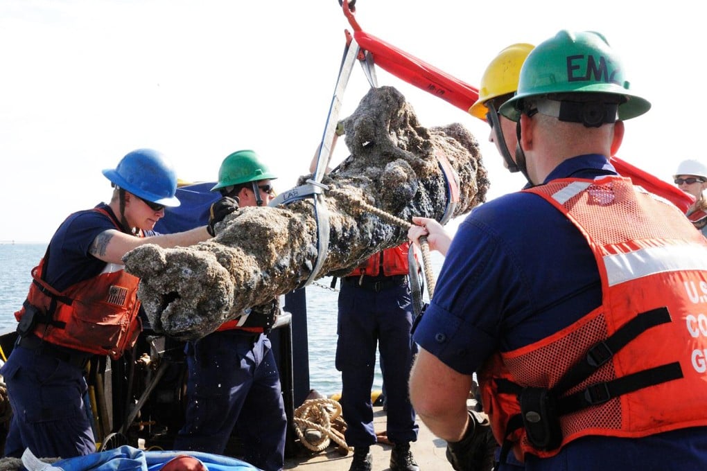 Members of the US Coast Guard and others as they raise a cannon from the sunken ship off the coast of North Carolina.  Photo: AFP