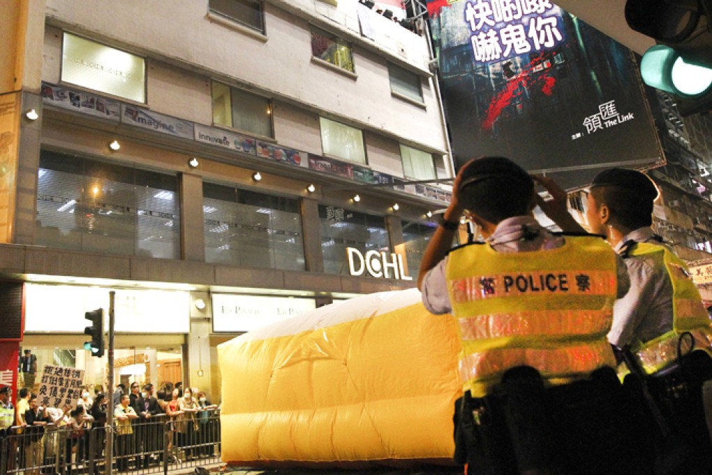 Protesters look down from the DCHL office in Causeway Bay last night. An air cushion was inflated on the road below. Photo: Edmond So