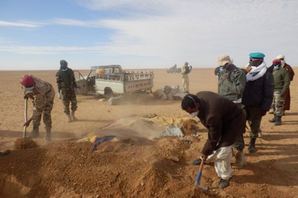 Volunteers and officials dig graves to inter the bodies of migrants who died of thirst after their truck (in background) broke down while attempting to cross the Sahara Desert. Photo: AP