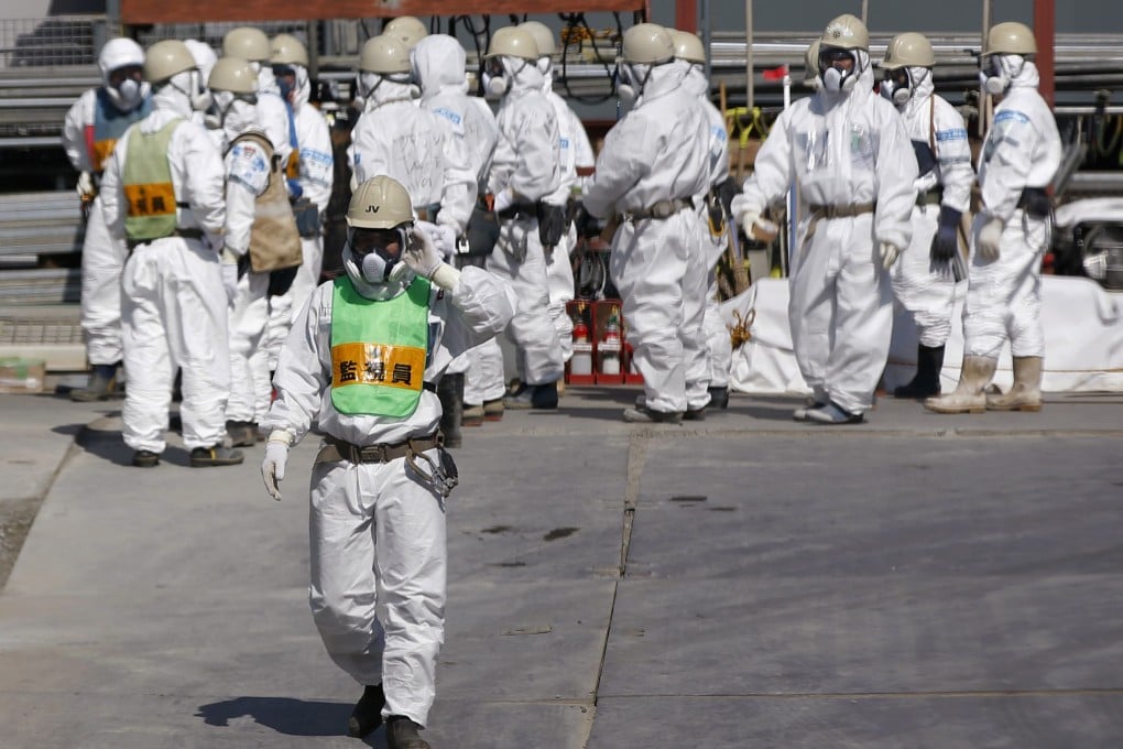 Workers wearing protective suits and masks at the Fukushima plant. A ruling party official has questioned a government plan to let evacuees return home. Photo: Reuters