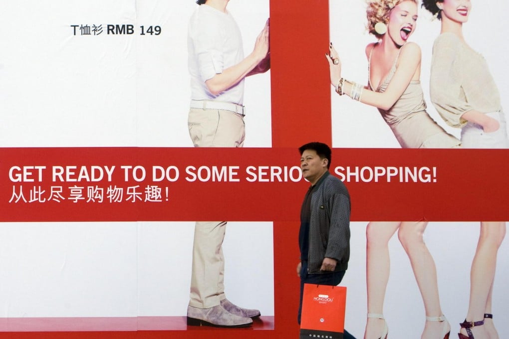 A shopper walks past a billboard for an upcoming H&M store in Beijing. Photo: Bloomberg