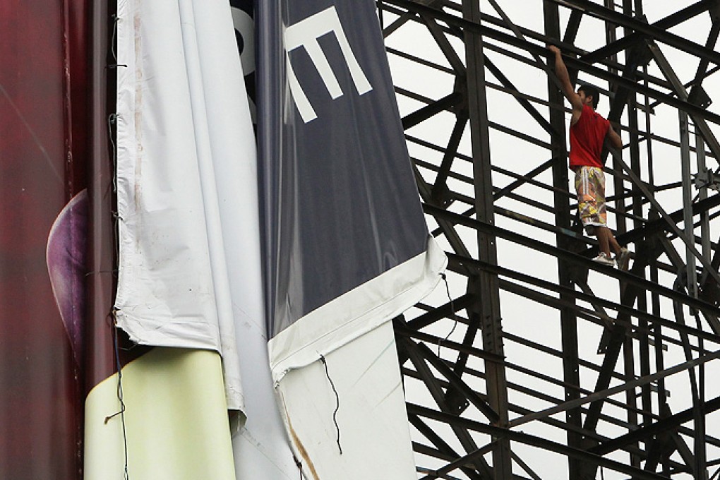 Filipino workers take down a large billboard sign in anticipation of strong winds brought by an upcoming typhoon in Makati city, south of Manila, Philippines, on Thursday. Photo: EPA