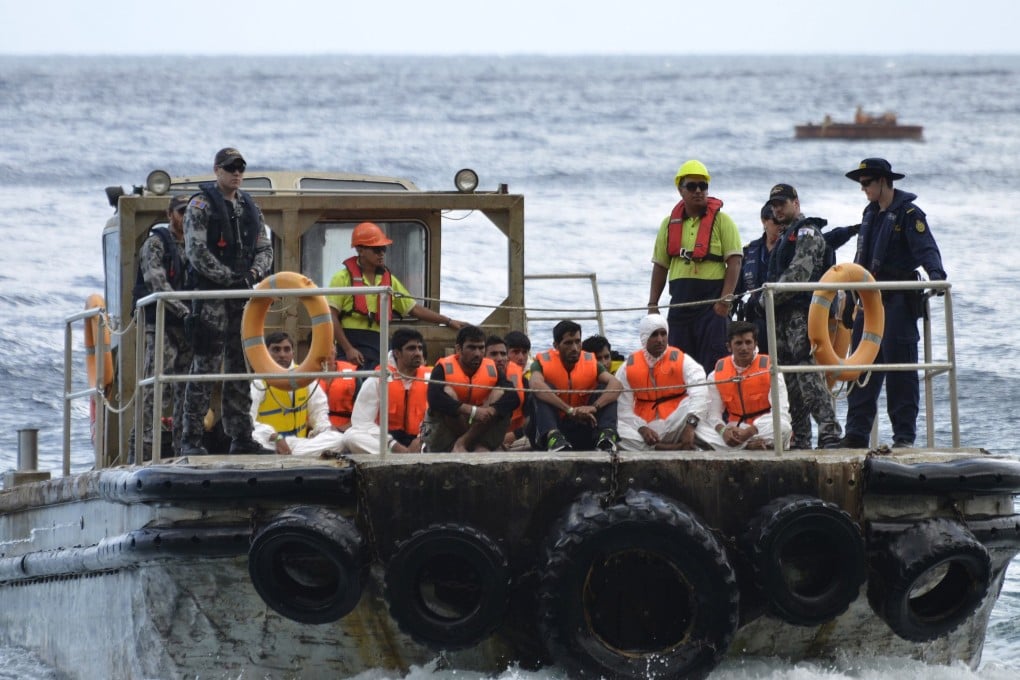 Australian customs officials and navy personnel escort rescued asylum-seekers onto Christmas Island. Photo: Reuters
