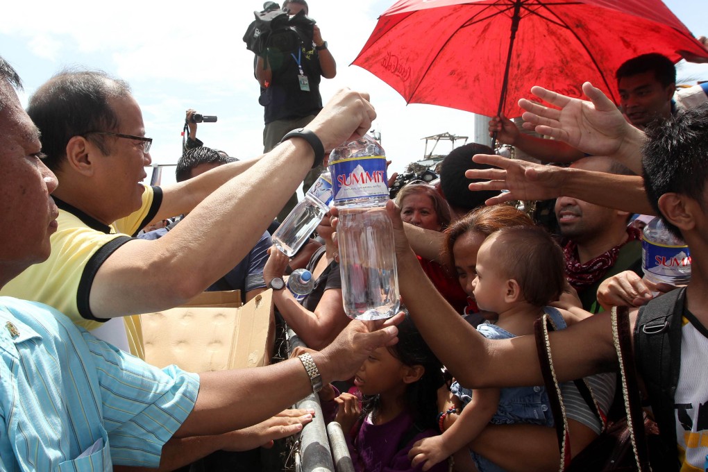 Philippines' President Benigno Aquino III distributes water to families displaced by Super Typhoon Haiyan. Photo: AFP