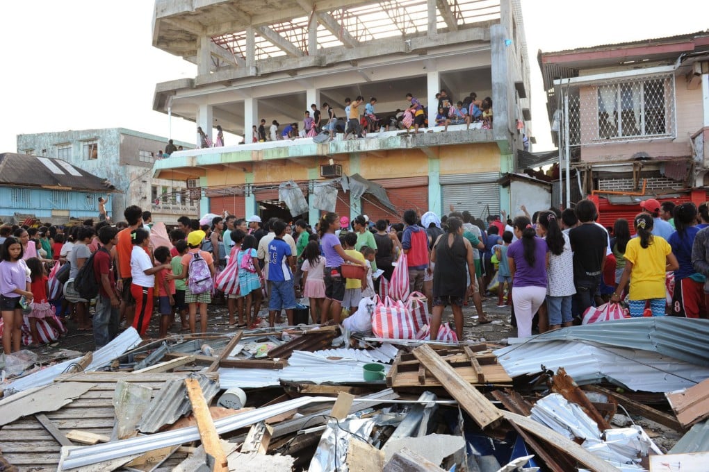 Surviving residents of the town of Guiuan, hit first by the typhoon, watch as others loot a warehouse of food and other items. Photo: AP
