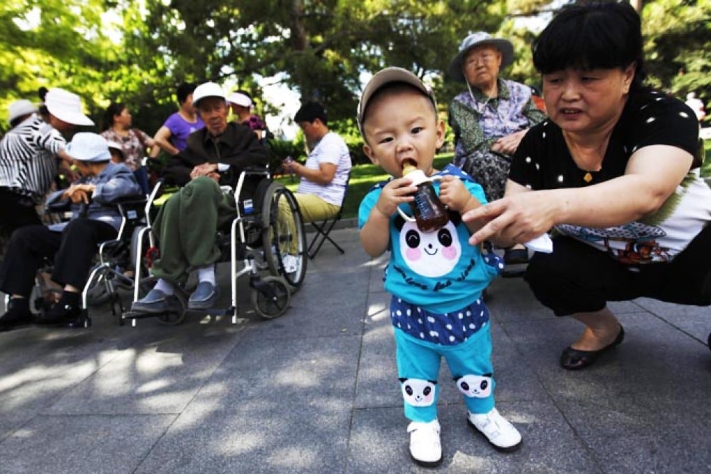 A Chinese woman helps her child with a water bottle in a park in Beijing. Photo:EPA
