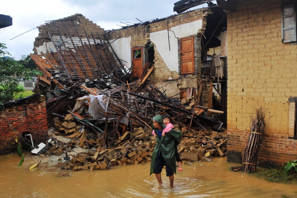 A resident carrying a child stands in a flooded street in Yong'an Town of Bobai County, southwest China's Guangxi province. Photo: Xinhua