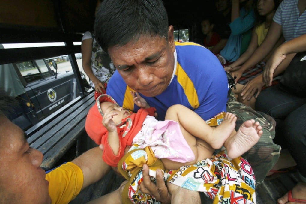 A child, one of the survivors who was evacuated from the disaster zone, is carried into a military truck with her family after they arrive via a military plane in Manila. Photo: Reuters