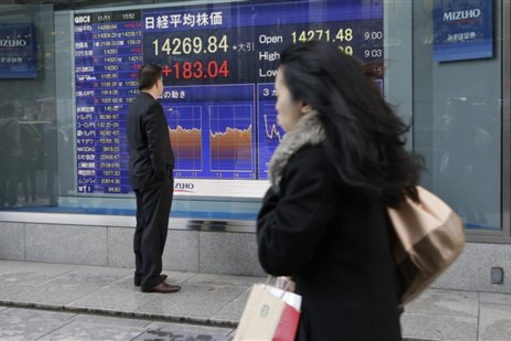 A man looks at an electronic stock board of a securities firm showing Japan's benchmark Nikkei 225 that gained 183.04 points, or 1.30 percent, and closed at 14,269.84 in Tokyo, Monday, Nov. 11, 2013. Asian stock markets made a lackluster start to the week after unexpectedly strong U.S. economic growth and hiring reinforced expectations that the Federal Reserve will start cutting back stimulus soon. (AP Photo/Shizuo Kambayashi)