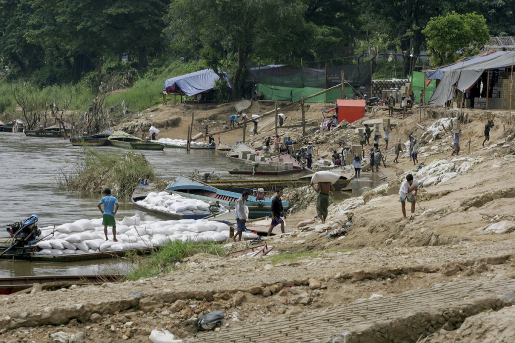Workers load sacks onto boats on the Myanmar side of the Moei River.