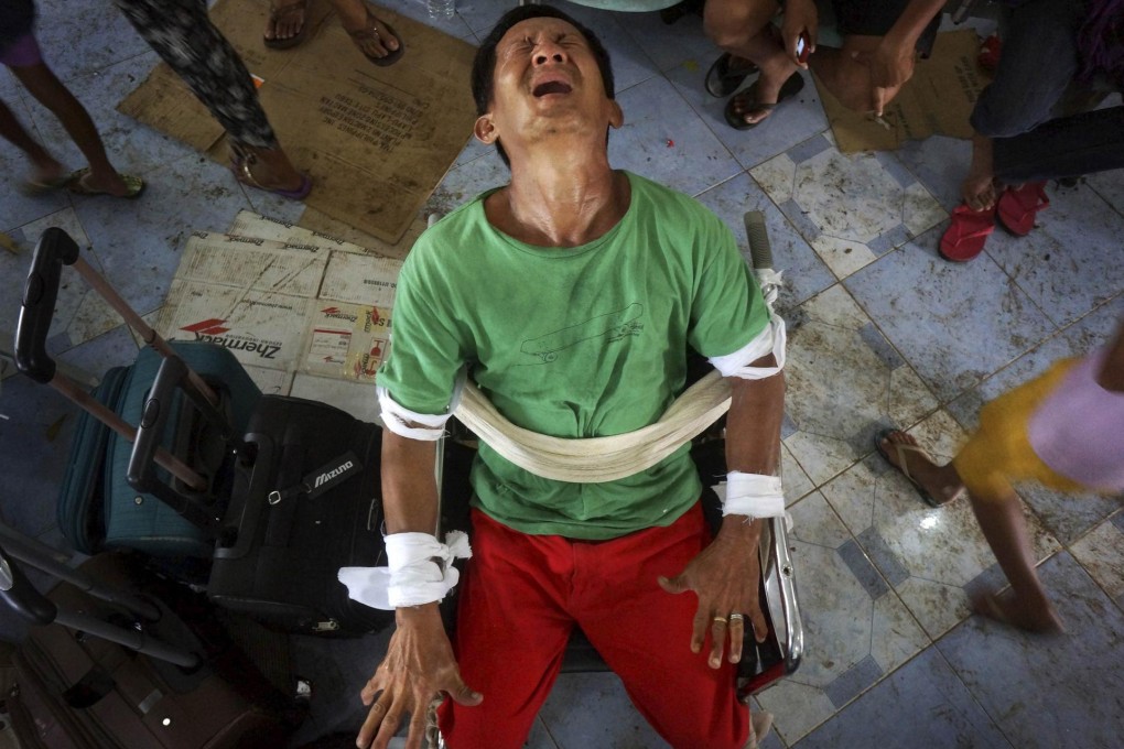 Gerardo Alvarez, 53, whose mother and sister died, is overwhelmed with grief. He had to be strapped to a wheelchair and medicated at an airbase in Cebu. Photo: Reuters