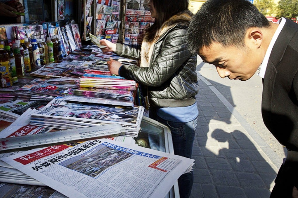 A man reads the front page of a Chinese newspaper showing a photo of the typhoon damage in the Philippines and characters that read "US and Europe hype up Chinese aid to Philippines as 'Not Generous'", in Beijing on Thursday. Photo: AP