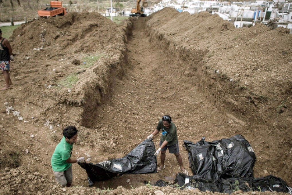 Volunteers carry the body of a typhoon victim in a bag during a mass burial on the outskirts of Tacloban yesterday. Photo: AFP