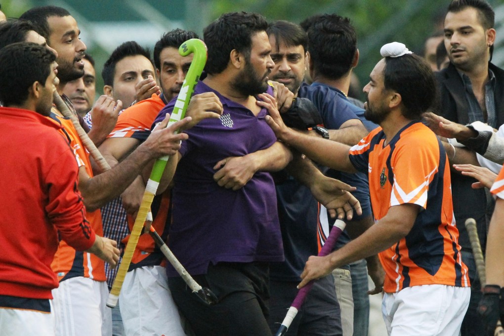 A Khalsa player (right) tries to calm down irate fans during a pitch melee at Happy Valley on Sunday. Photo: Edward Wong