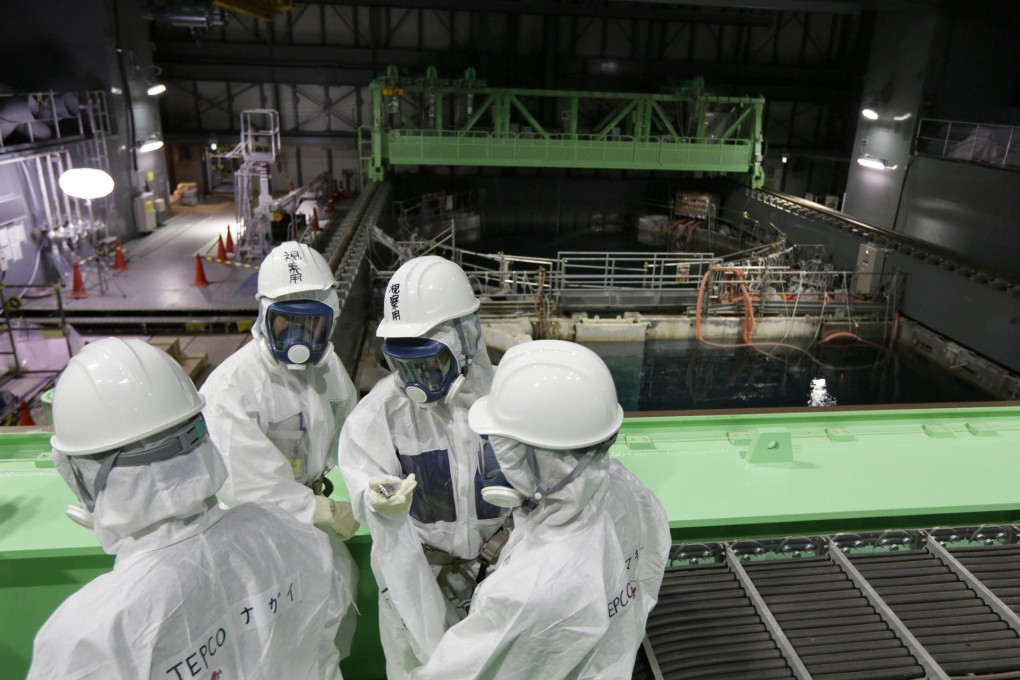 Employees and journalists in protective suits and masks examine the spent fuel pool at the damaged Fukushima nuclear plant. Photo: AP