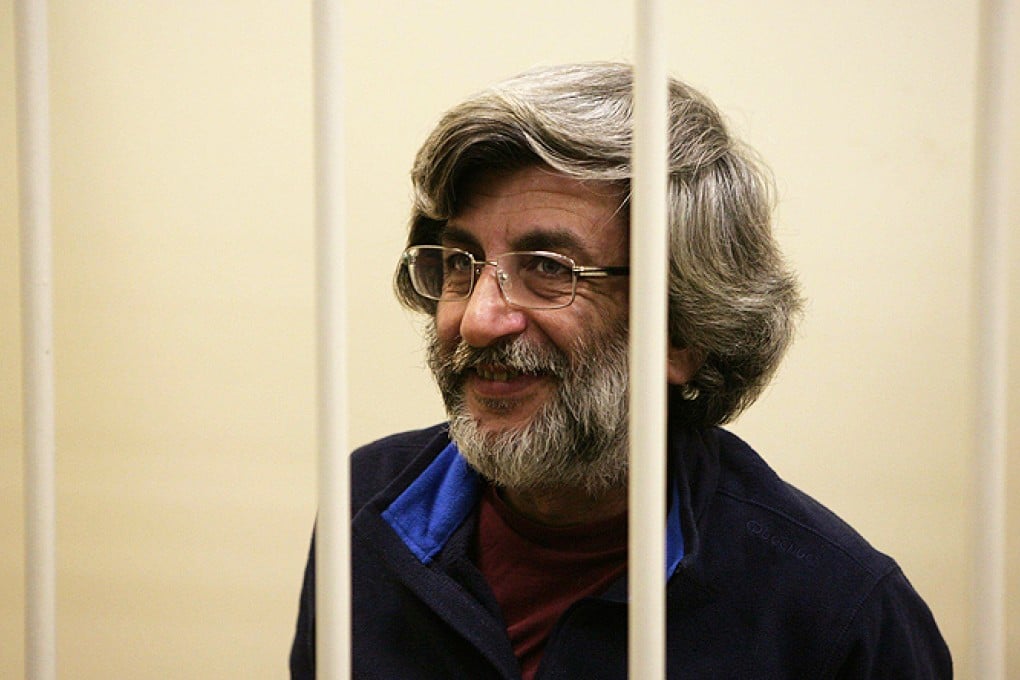 Greenpeace International activist Andrey Allakhverdov smiles from inside a barred enclosure during a court session in St Petersburg, Russia. Photo: AP