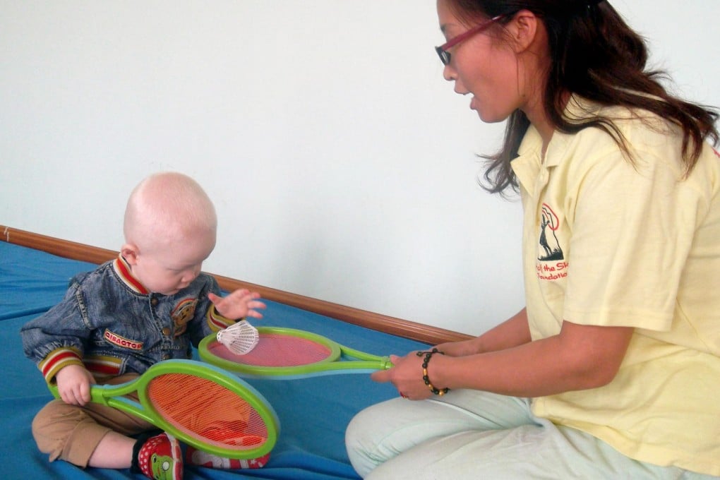 At an orphanage in Luoyang, little Hechuan, who has albinism, plays with Chen Baomei, a nanny trained and employed by Half the Sky Foundation. Photo: SCMP