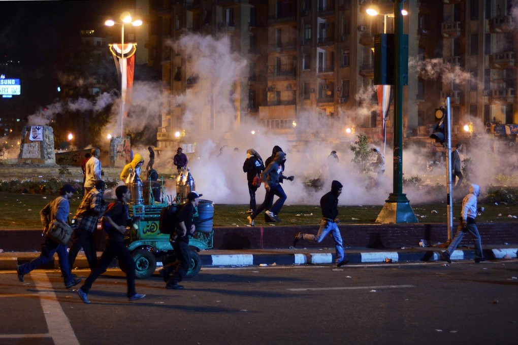 Egyptian anti-military demonstrators run for cover from tear gas fired by riot police during clashes in Tahrir Square. Photo: AFP