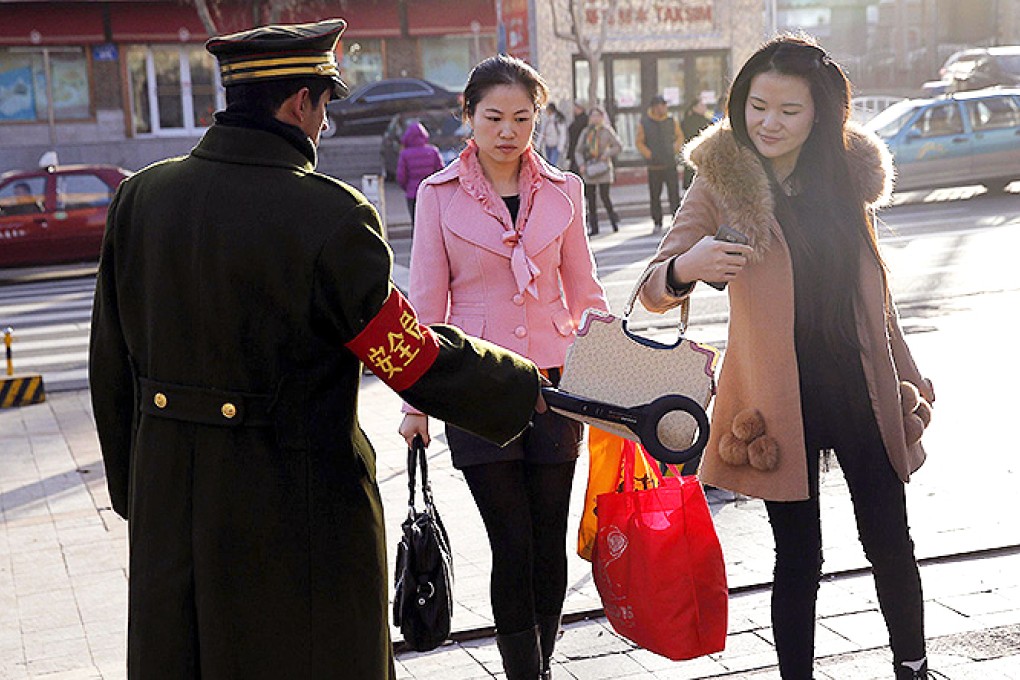 A security officer scans a pedestrian with a detector on a street in Urumqi. Photo: Reuters
