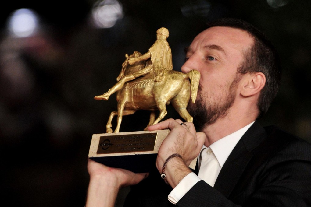 Director Alberto Fasulo kisses his best film award forTir. Photo: AFP