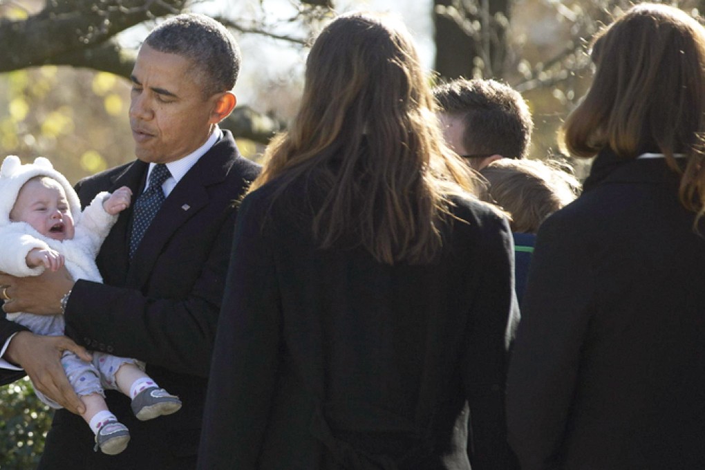 Barack Obama cradles a young member of the extended Kennedy family during a ceremony at which he laid a wreath at the grave of John F. Kennedy. Photo: Reuters