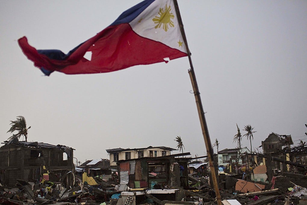 A Philippines flag flies over a destroyed neighbourhood in Tacloban, Philippines, on Friday as the official death toll from Typhoon Haiyan surpassed 5,200. Photo: AP