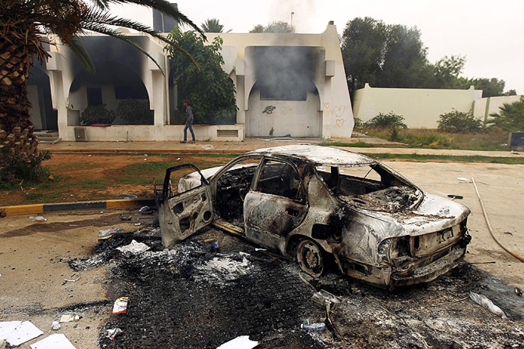 The wreckage of a burnt car is seen outside a building used by Ansar al-Sharia militia after it was torched by residents in Benghazi. Photo: AFP