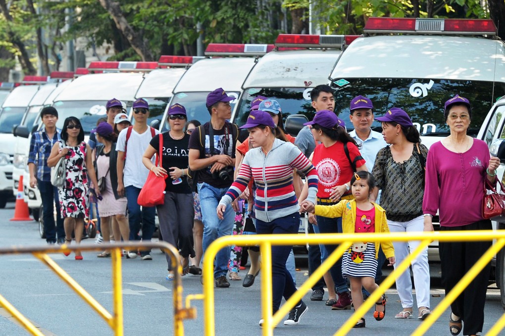 Foreign tourists walk past police vans outside the parliament building in Bangkok on Tuesday. Photo: AFP