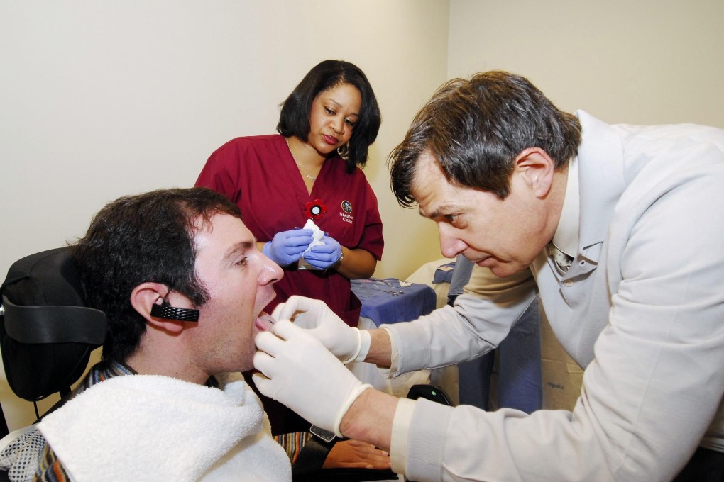 Jason Disanto’s tongue is pierced (at left) to allow him to pilot a wheelchair using the magnetic system. Photo: Reuters