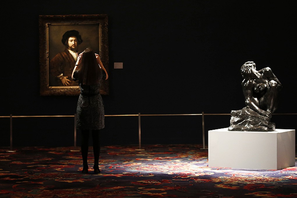 A woman takes a picture of Rembrandt's 'Portrait of a Man with Arms Akimbo' at the selling exhibition of Modern Masters during Sotheby's Beijing Art Week in Beijing. Photo: Reuters