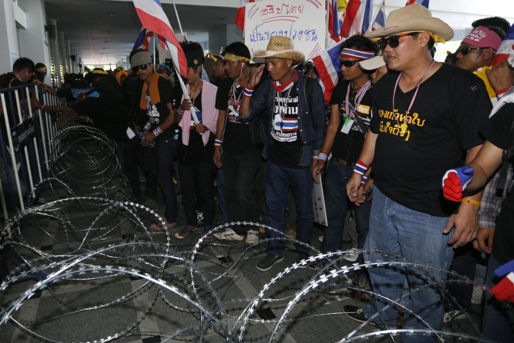 Thai anti-government protesters behind razor wire at the Department of Special Investigation in Bangkok on Saturday. Photo: EPA
