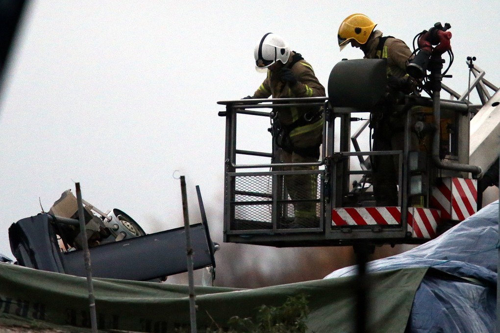 Scottish Fire and Rescue officers look at the exposed part of the helicopter tail fin protruding from the Glasgow pub’s roof. Photo: AP