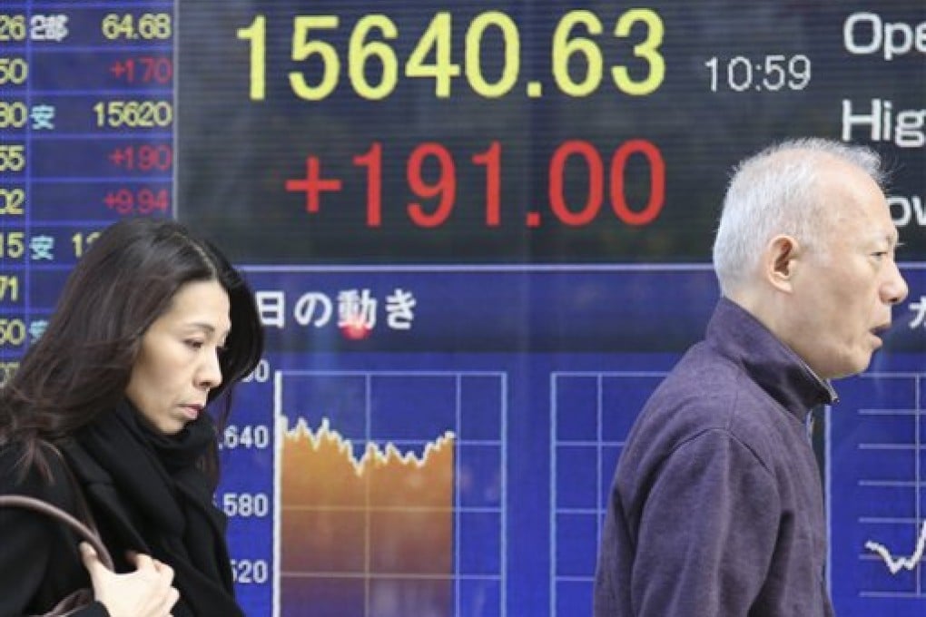 People walk by an electronic stock board of a securities firm in Tokyo, Thursday, Nov. 28, 2013. Japanese stocks jumped on Thursday as the yen lingered near a six month low, leading a broader advance by Asian markets after U.S. benchmarks rose to record levels. (AP Photo/Koji Sasahara)