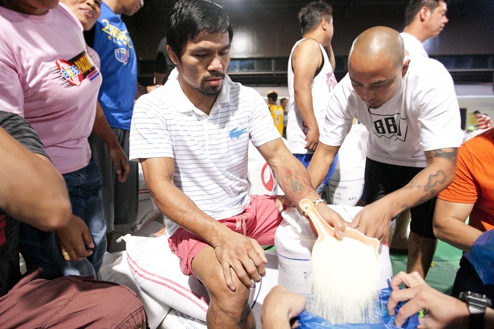 Filipino boxing icon Manny Pacquiao pours rice into a bag at a relief centre in General Santos, southern Philippines. Photo: AP